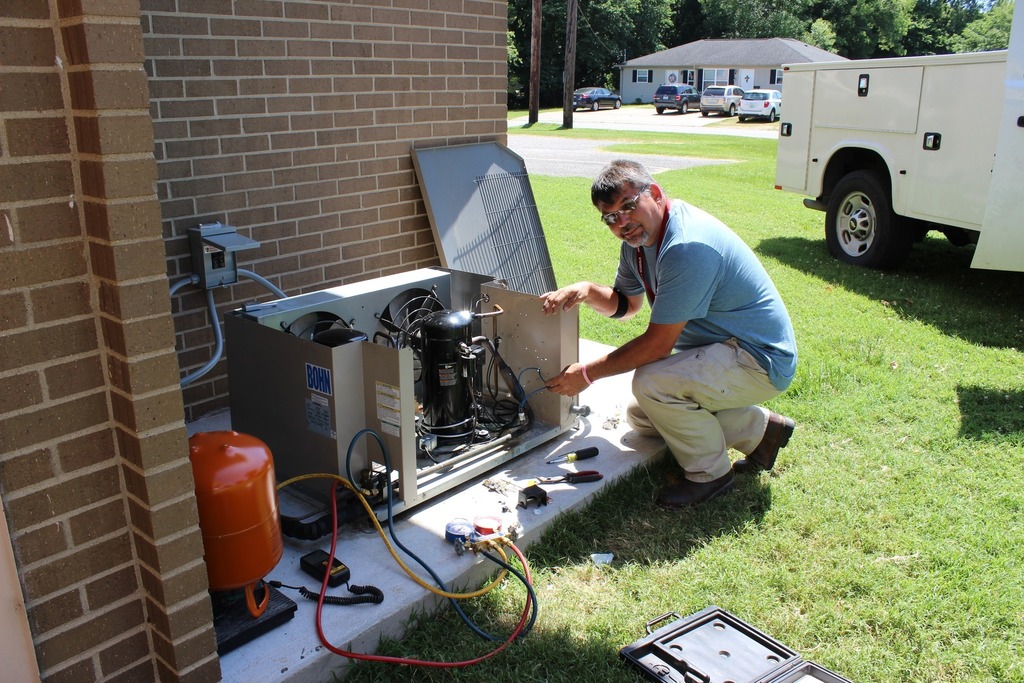 Man from maintenance crew working on air conditioning unit.
